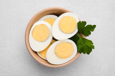 Fresh hard boiled eggs and parsley on light grey table, top view