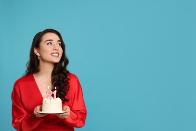 Photo of Coming of age party - 21st birthday. Woman holding cake with number shaped candles on light blue background, space for text