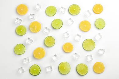 Photo of Lemonade layout with ice cubes, lime and orange slices on white background, top view
