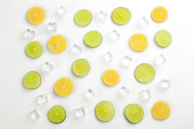 Lemonade layout with ice cubes, lime and orange slices on white background, top view