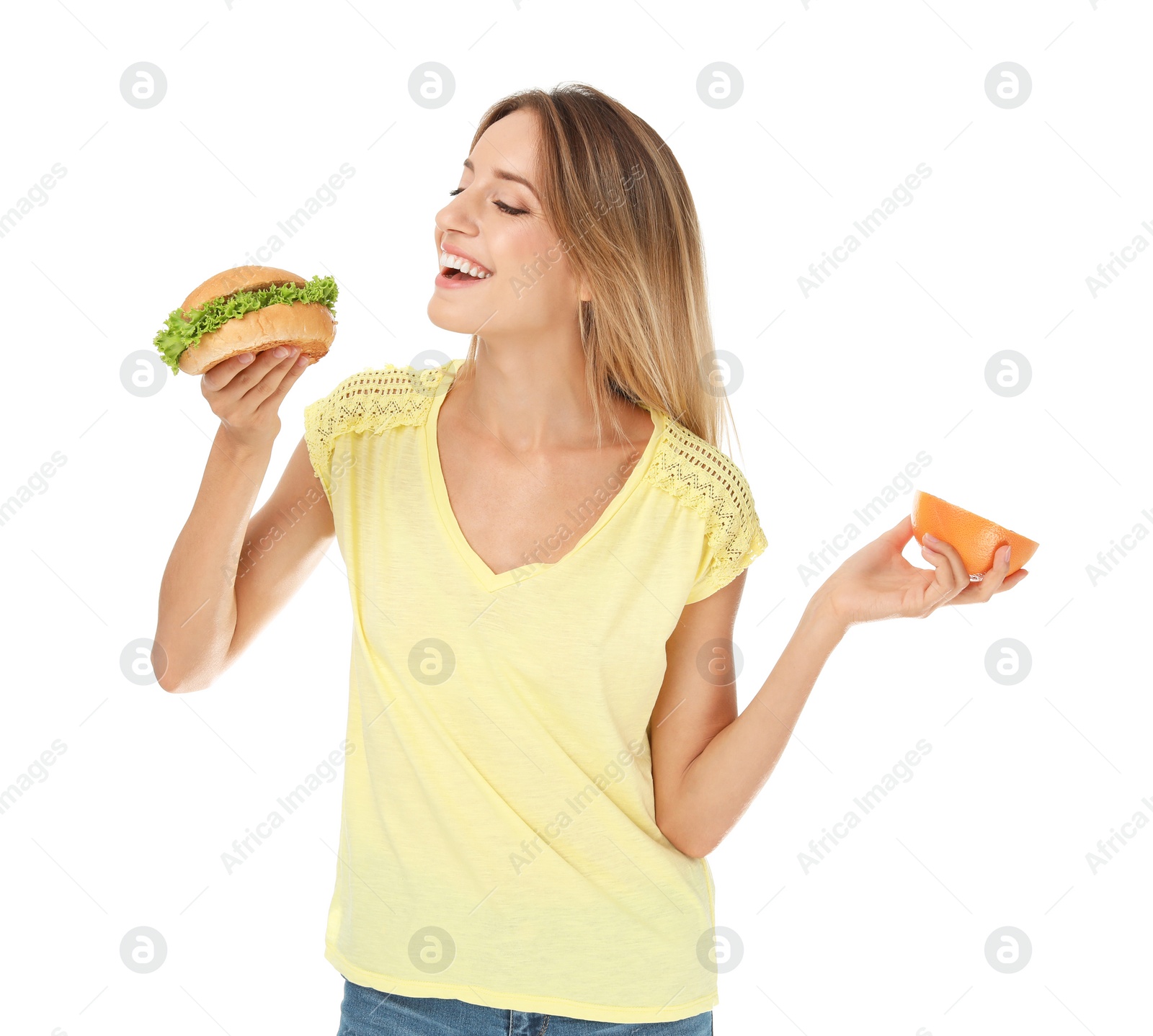 Photo of Young woman holding burger and grapefruit on white background. Choice between diet and unhealthy food