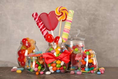 Jars with different delicious candies on grey table