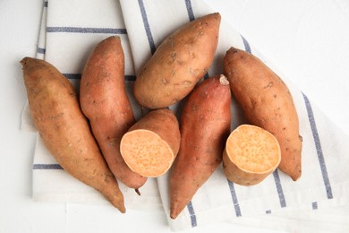 Photo of Whole and cut ripe sweet potatoes on white table, top view