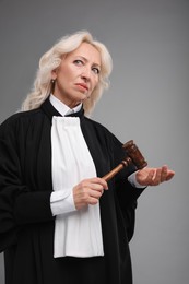 Photo of Senior judge with gavel on grey background
