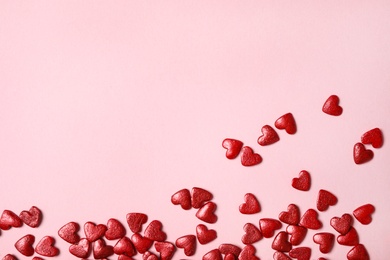 Photo of Red heart shaped sprinkles on pink background, flat lay. Space for text
