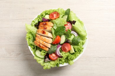Delicious salad with chicken and vegetables on wooden table, top view
