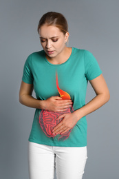 Image of Woman suffering from stomach pain on grey background