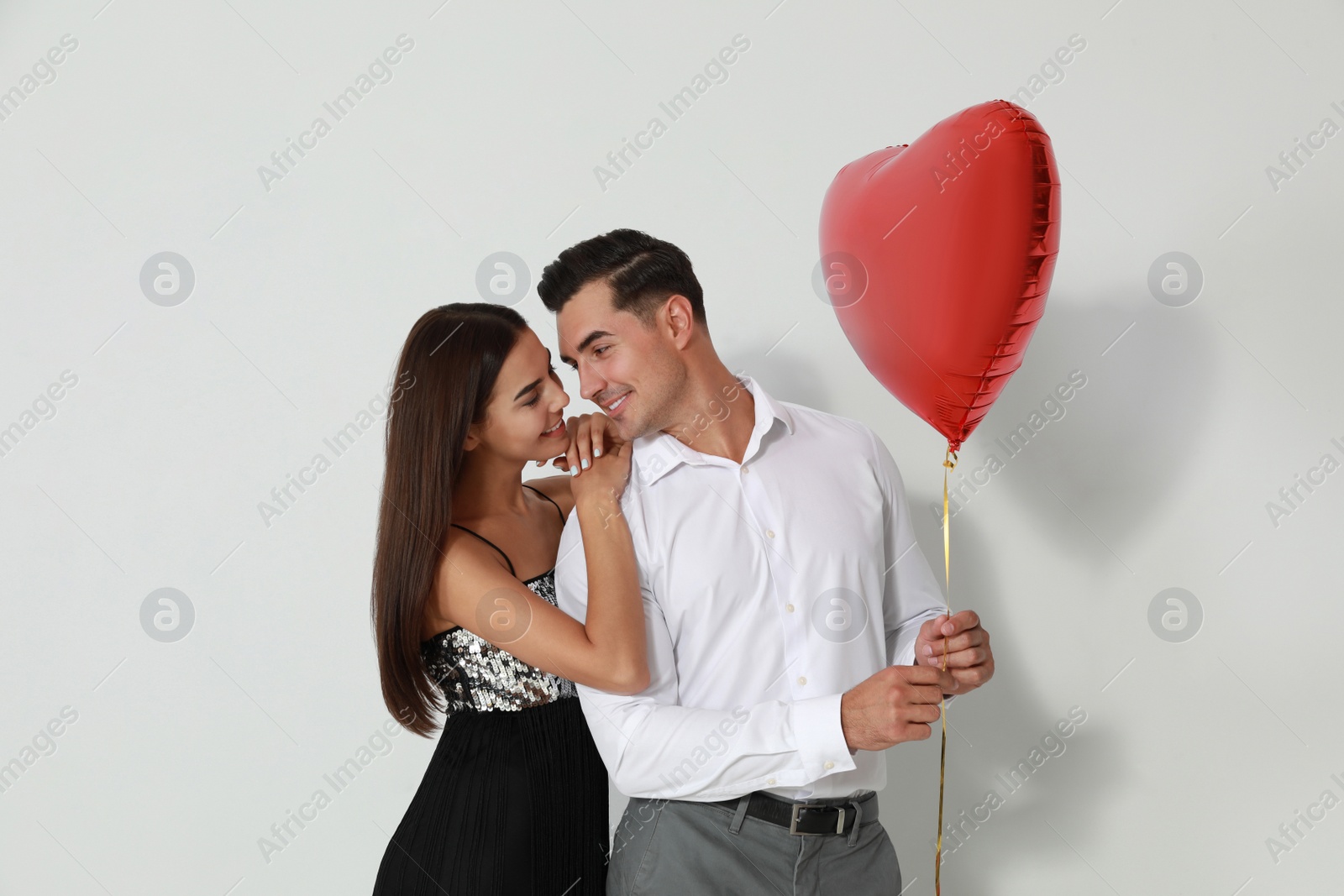 Photo of Beautiful couple with heart shaped balloon on light background