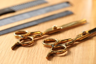 Hairdresser tools. Different scissors and combs on wooden table, closeup