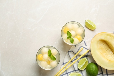 Photo of Glasses of melon ball cocktail with mint on light grey marble table, flat lay