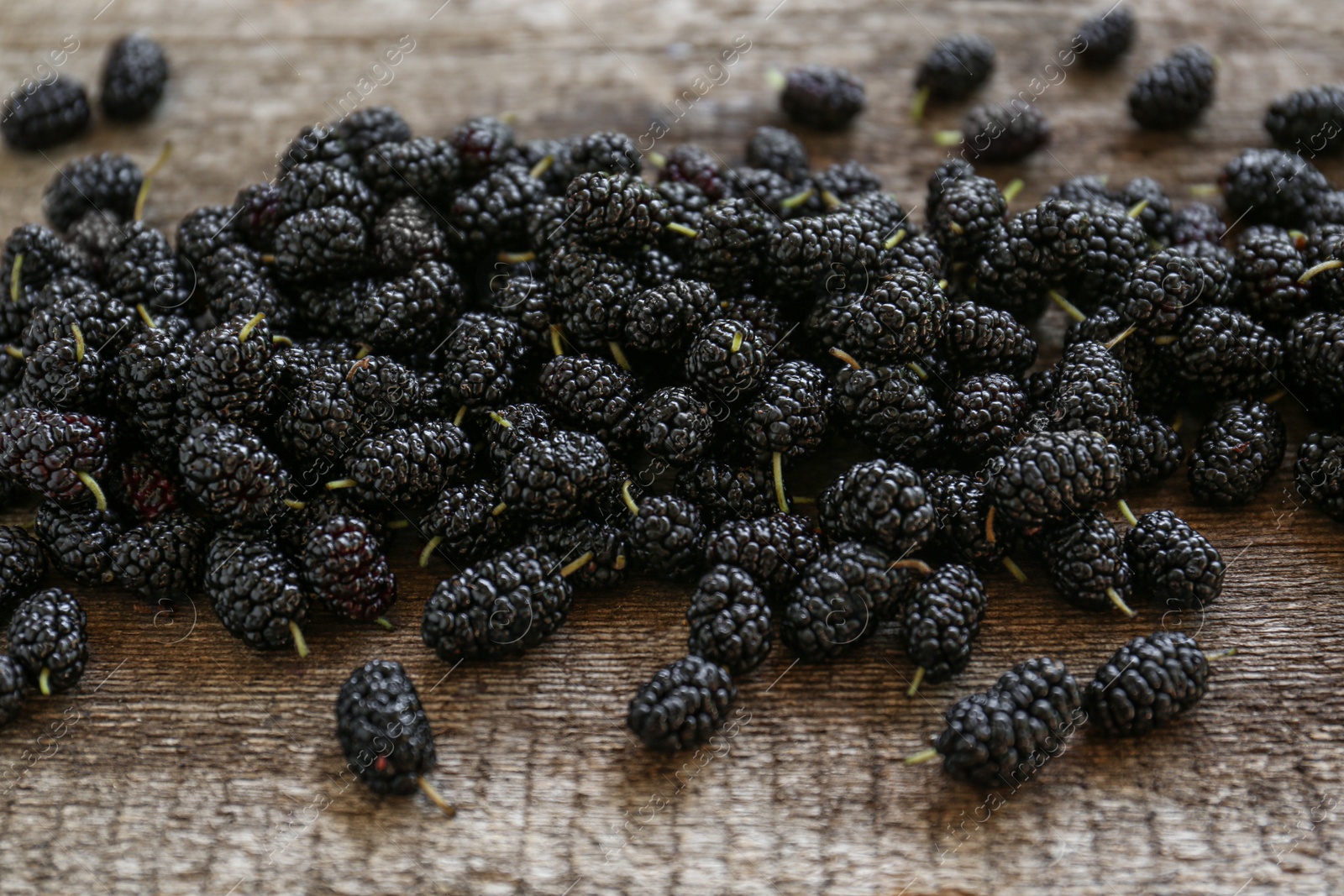 Photo of Heap of delicious ripe black mulberries on wooden table