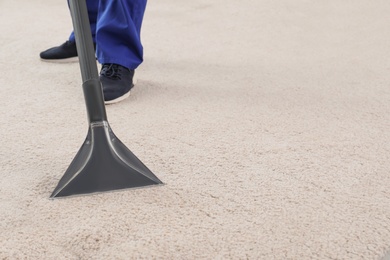 Photo of Man removing dirt from carpet with vacuum cleaner indoors, closeup. Space for text