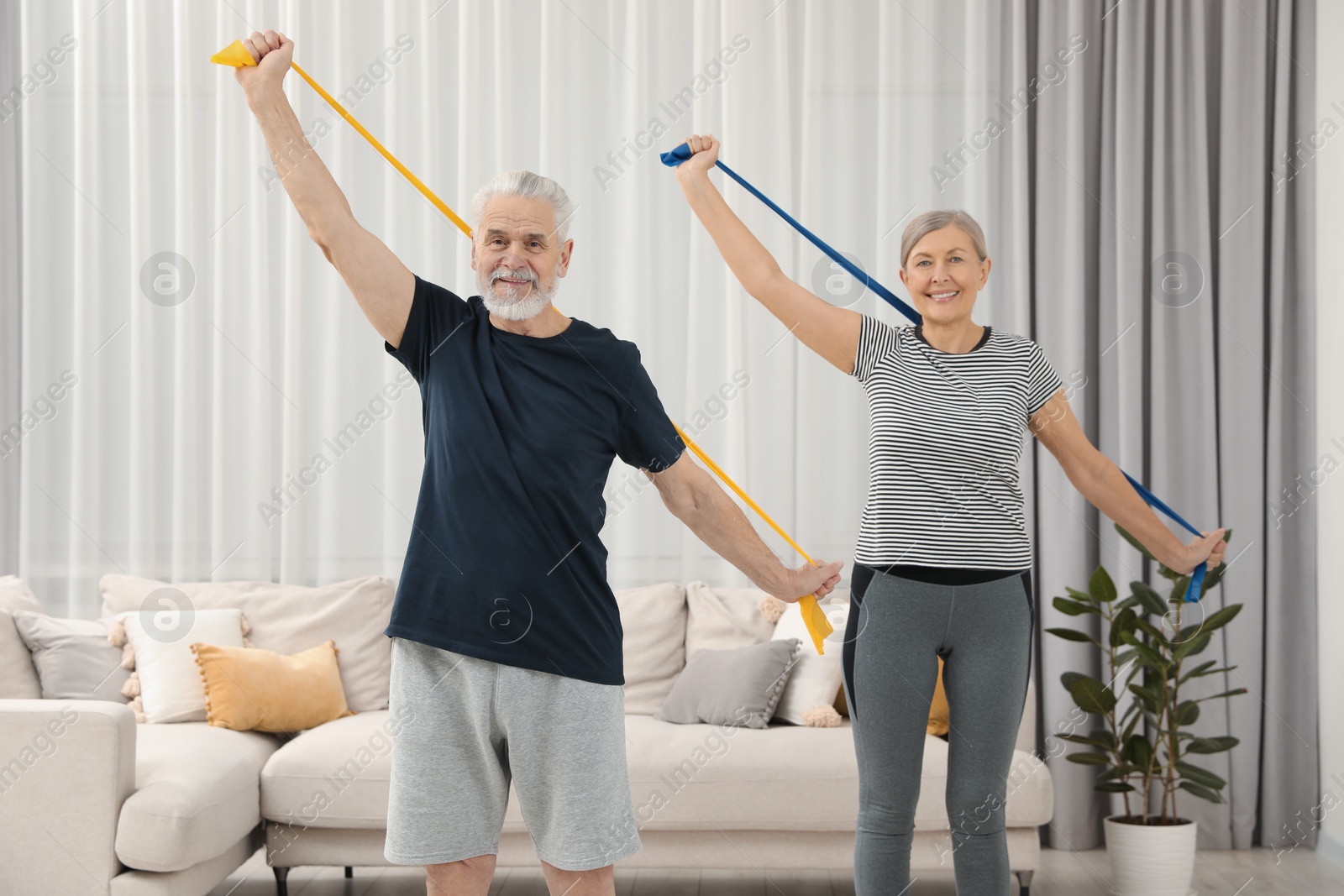 Photo of Senior couple doing exercise with fitness elastic bands at home