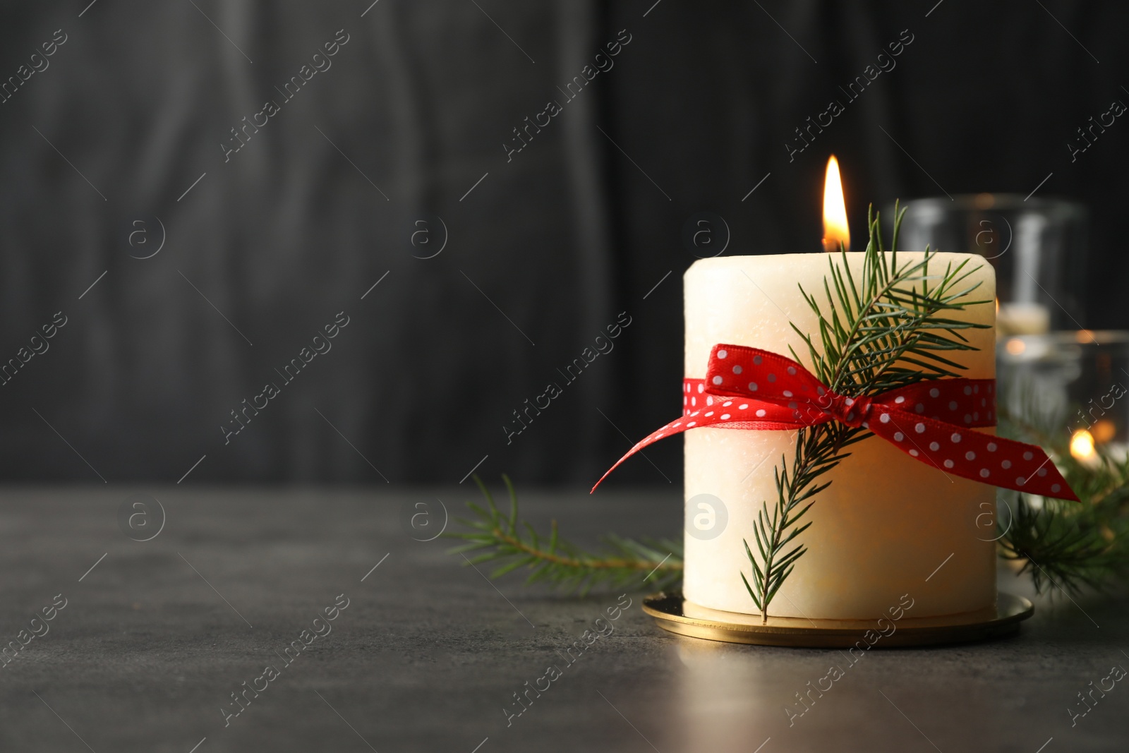 Photo of Burning candle with pinecone scent on black table, space for text