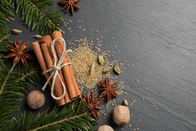 Photo of Different spices, nuts and fir branches on gray table, flat lay. Space for text