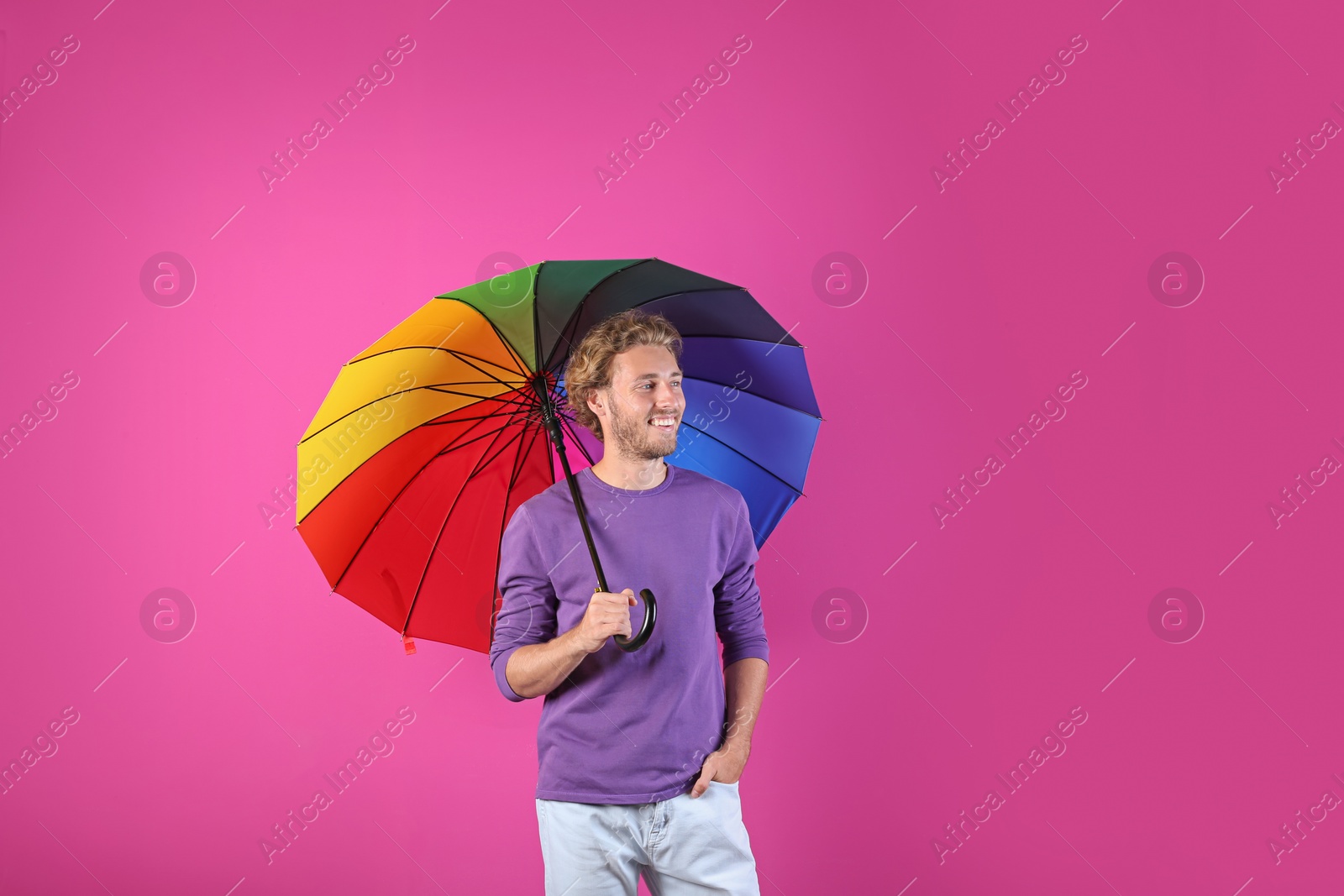 Photo of Man with rainbow umbrella on color background