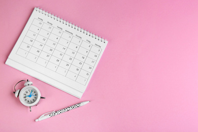 Calendar, pen and alarm clock on pink background, flat lay. Space for text