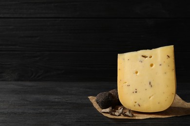 Photo of Delicious cheese and fresh truffles on black wooden table. Space for text