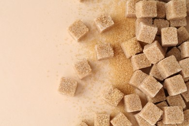 Photo of Brown sugar cubes on beige background, top view. Space for text