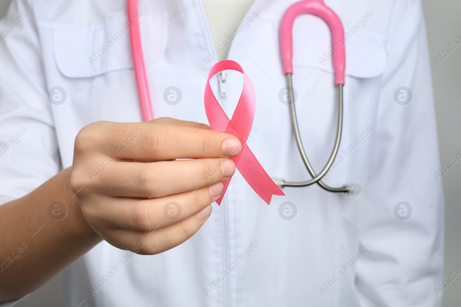 Photo of Doctor holding pink ribbon, closeup. Breast cancer awareness