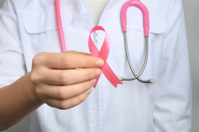 Doctor holding pink ribbon, closeup. Breast cancer awareness