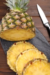Photo of Pieces of tasty ripe pineapple on wooden table, above view