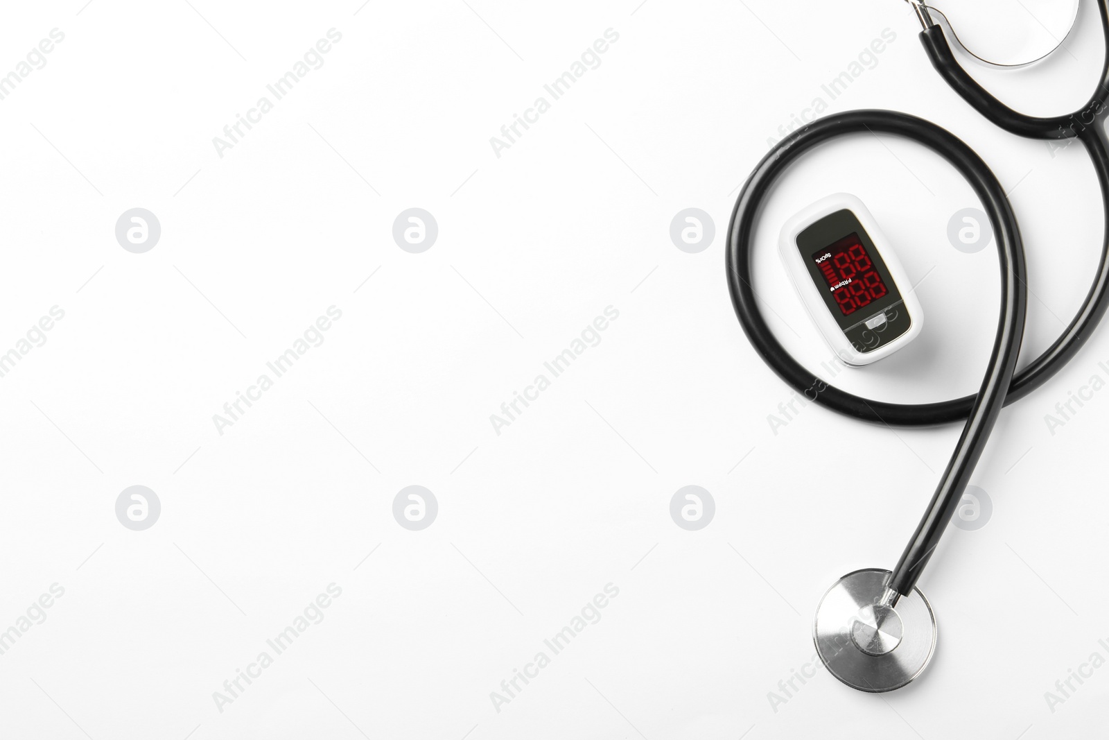 Photo of Modern fingertip pulse oximeter and stethoscope on white background, flat lay. Space for text