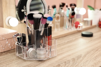 Photo of Organizer with cosmetic products for makeup on table near mirror. Space for text