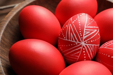 Photo of Red painted Easter eggs in wooden bowl, closeup