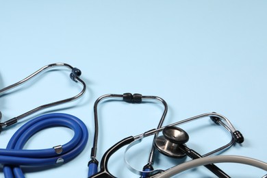 Photo of Stethoscopes on light blue background. Space for text