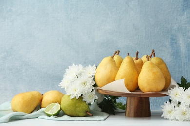 Stand with fresh ripe pears on table against color background