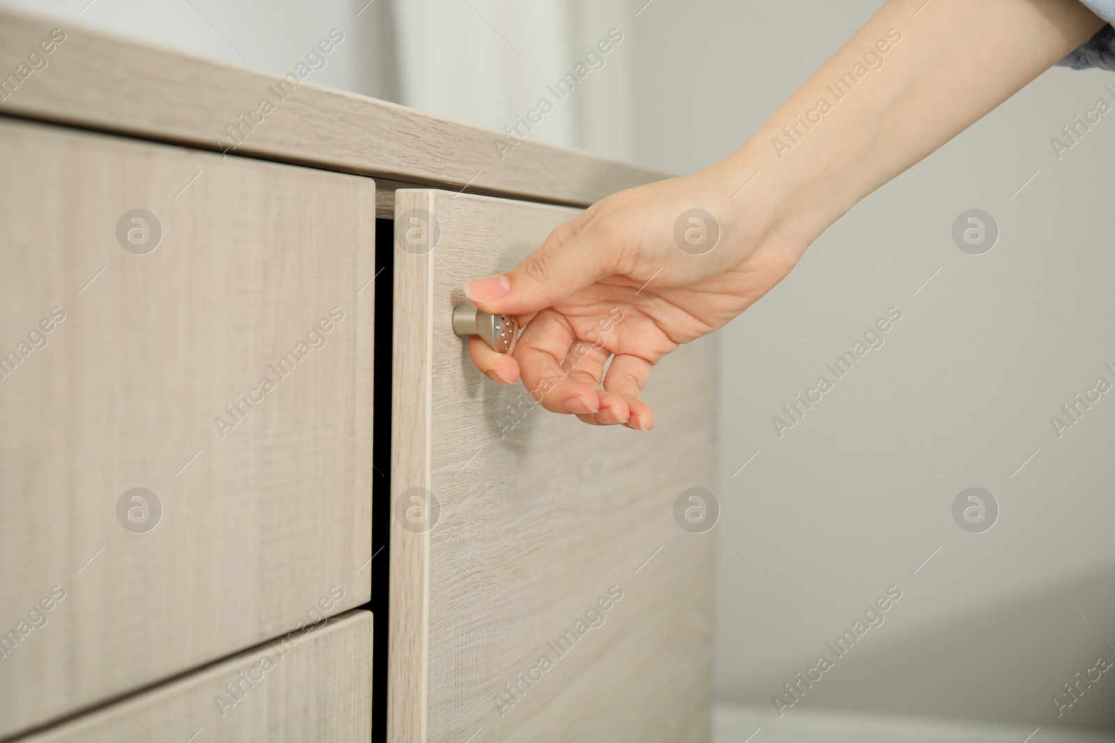 Photo of Woman opening cabinet door at home, closeup