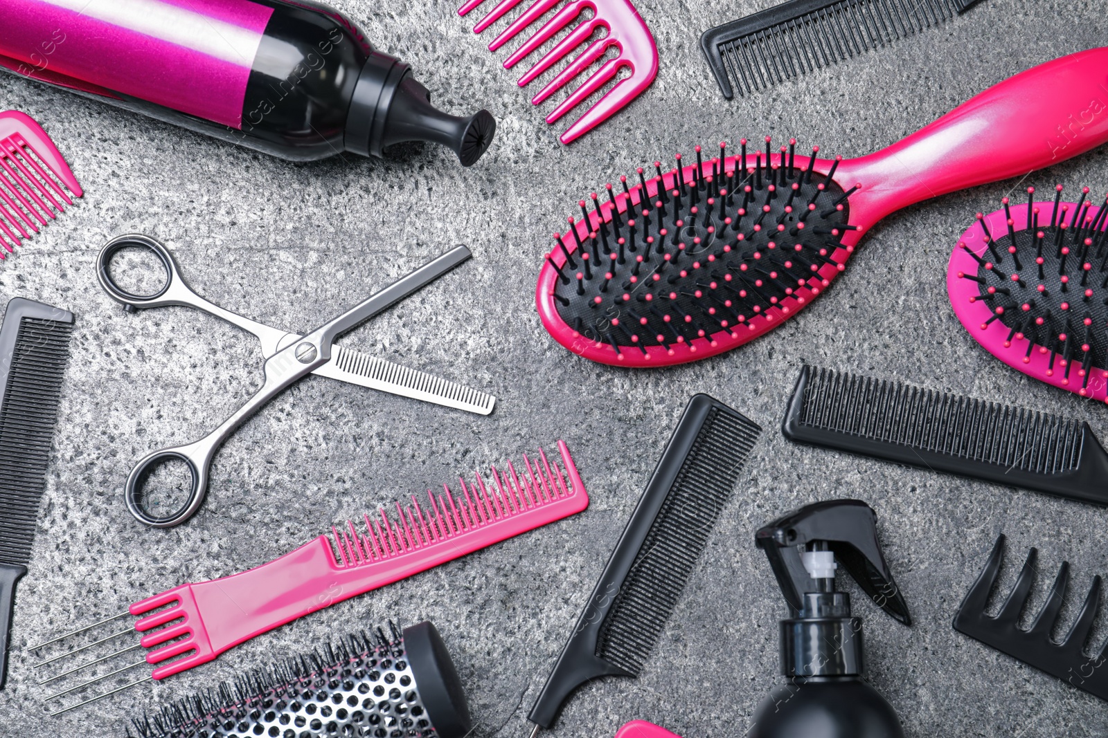 Photo of Flat lay composition of professional scissors and other hairdresser's equipment on grey table. Haircut tool