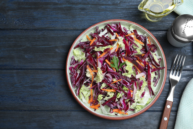 Photo of Fresh cabbage salad served on blue wooden table, flat lay