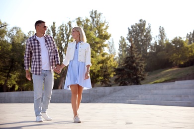 Happy couple walking along city street on summer day