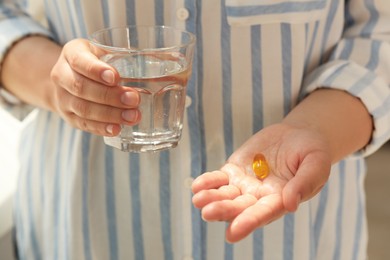 Photo of Young woman with dietary supplement pill and glass of water, closeup