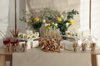 Photo of Delicious treats and glasses of drink on wooden table in room. Sweet buffet