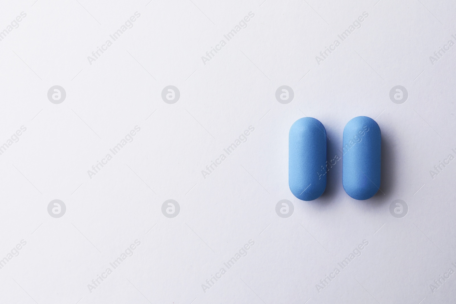 Photo of Pills and space for text on white background, top view. Potency problem