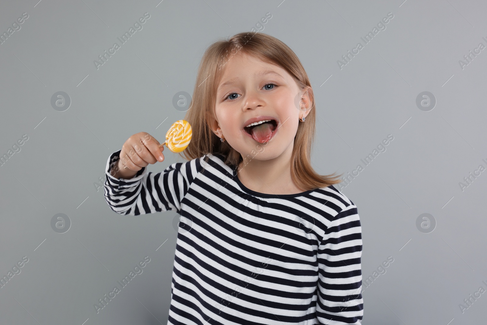 Photo of Portrait of happy girl with lollipop on light grey background