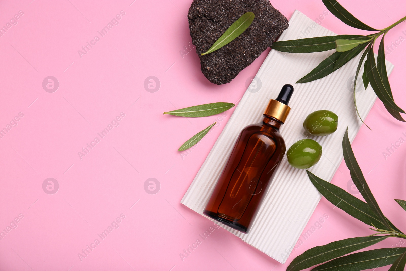 Photo of Cosmetic products with olive essential oil, stone and leaves on pink background, flat lay. Space for text