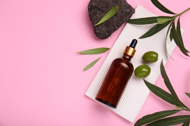 Photo of Cosmetic products with olive essential oil, stone and leaves on pink background, flat lay. Space for text