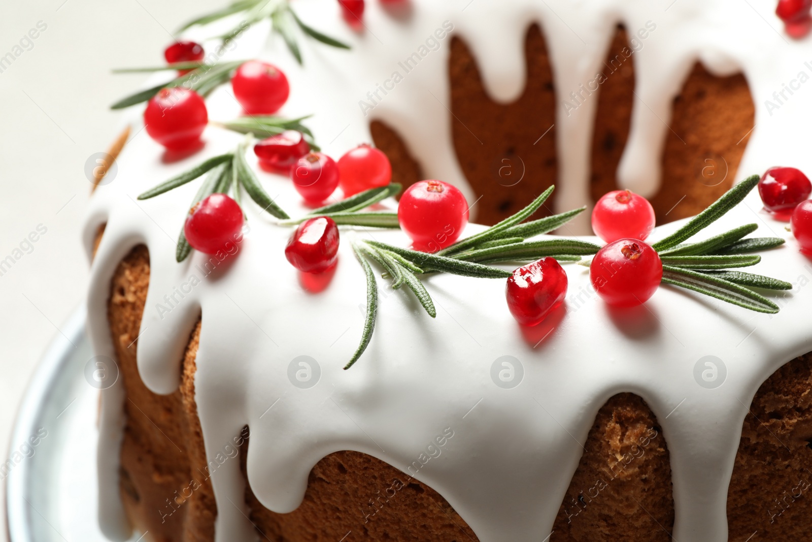 Photo of Traditional Christmas cake decorated with glaze, pomegranate seeds, cranberries and rosemary on table, closeup