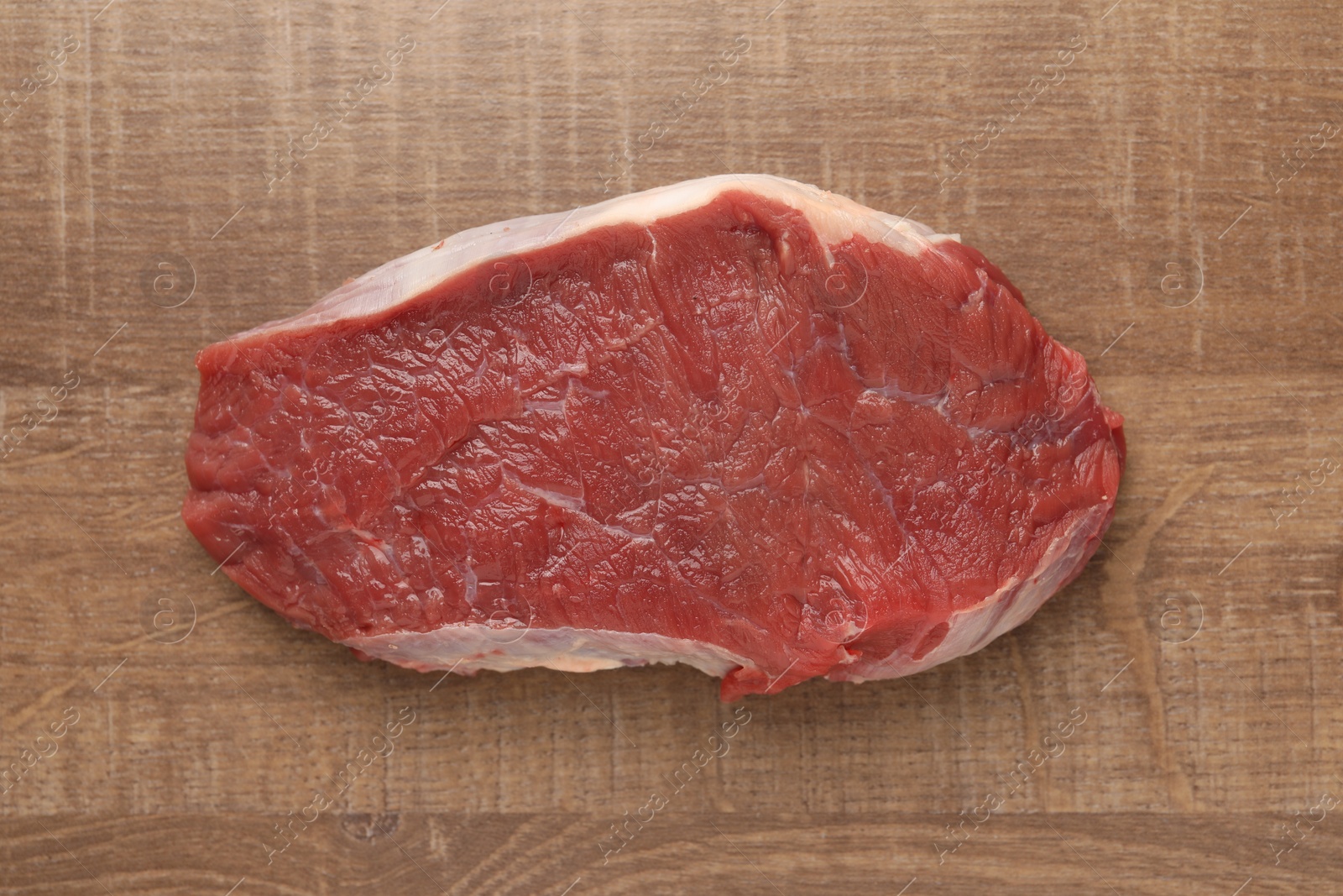 Photo of Piece of raw beef meat on wooden table, top view