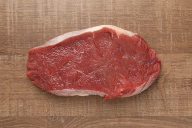 Photo of Piece of raw beef meat on wooden table, top view