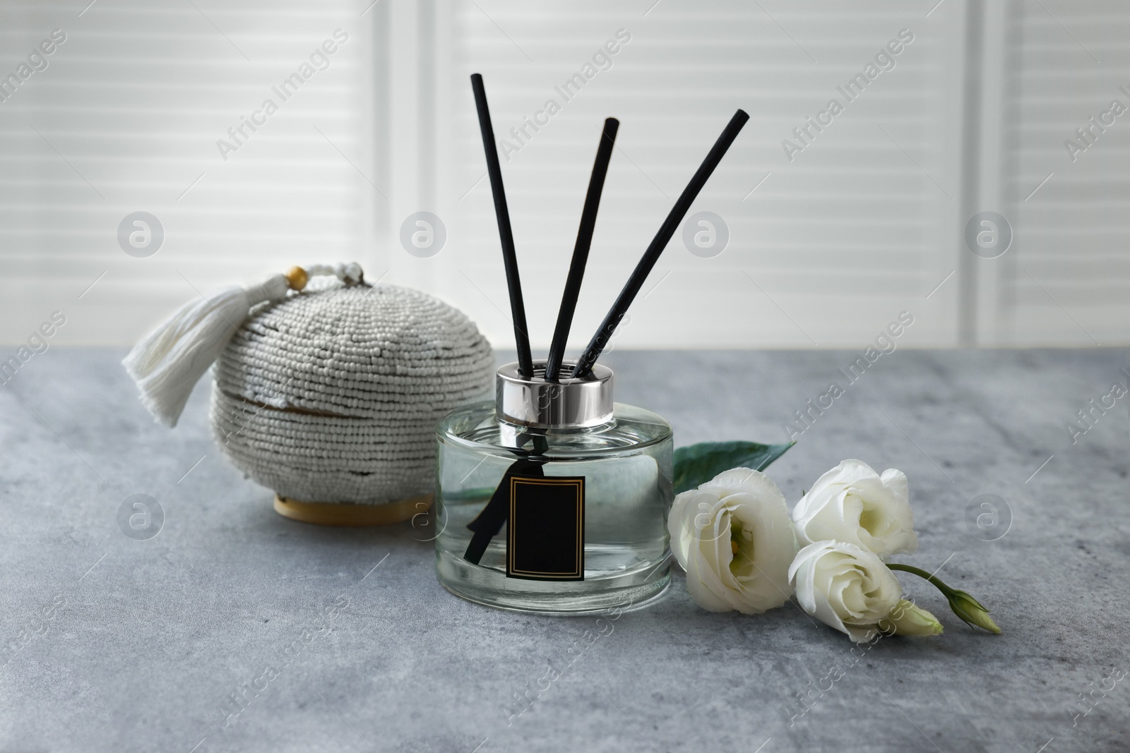 Photo of Reed diffuser, box and eustoma flowers on gray marble table