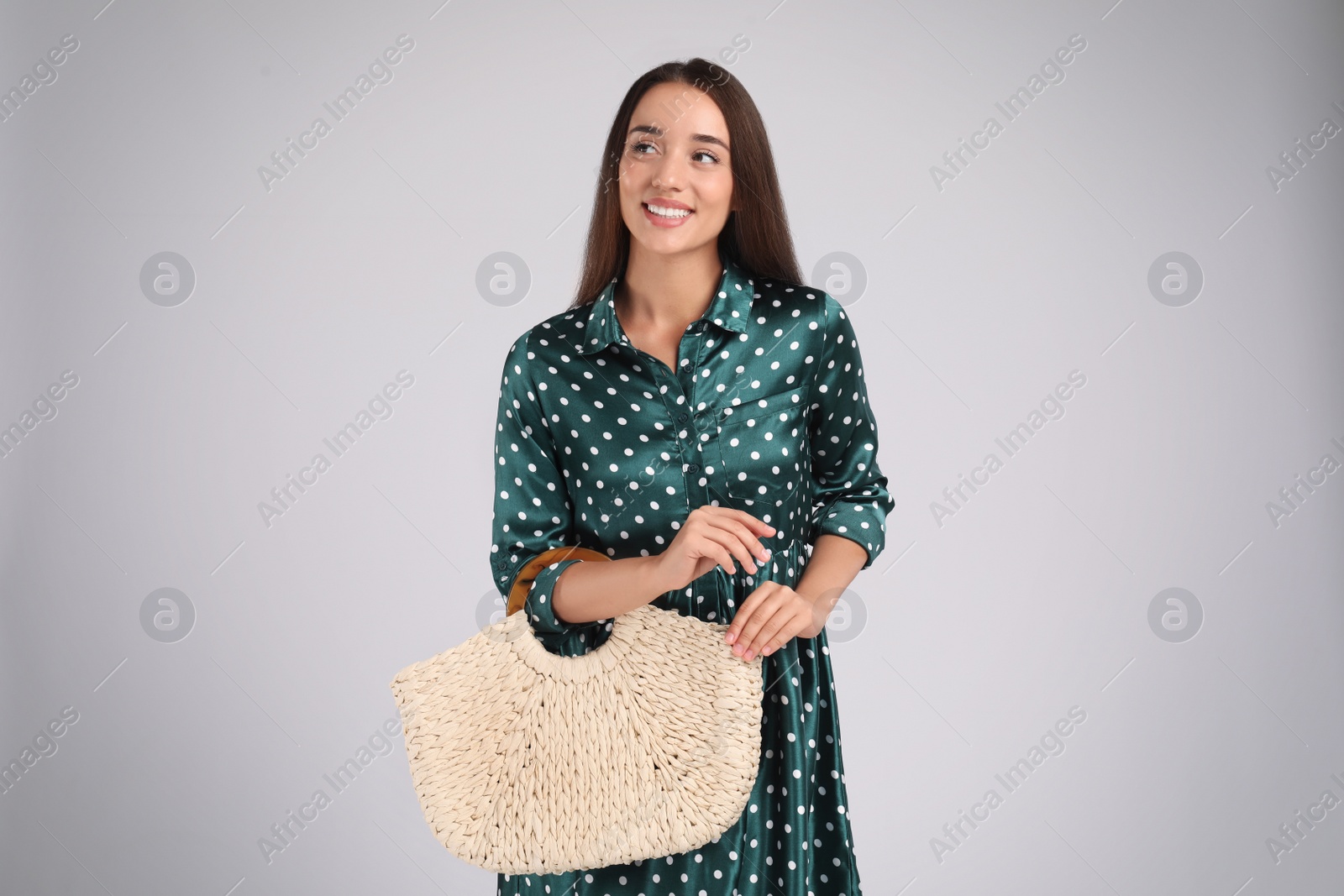 Photo of Young woman with stylish straw bag on light grey background