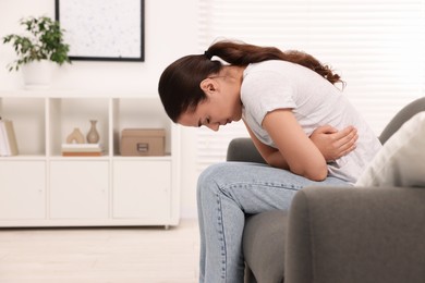 Woman suffering from abdominal pain on sofa at home. Unhealthy stomach