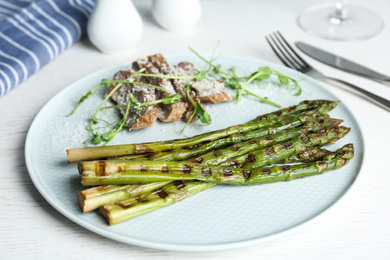 Tasty meat served with grilled asparagus on plate