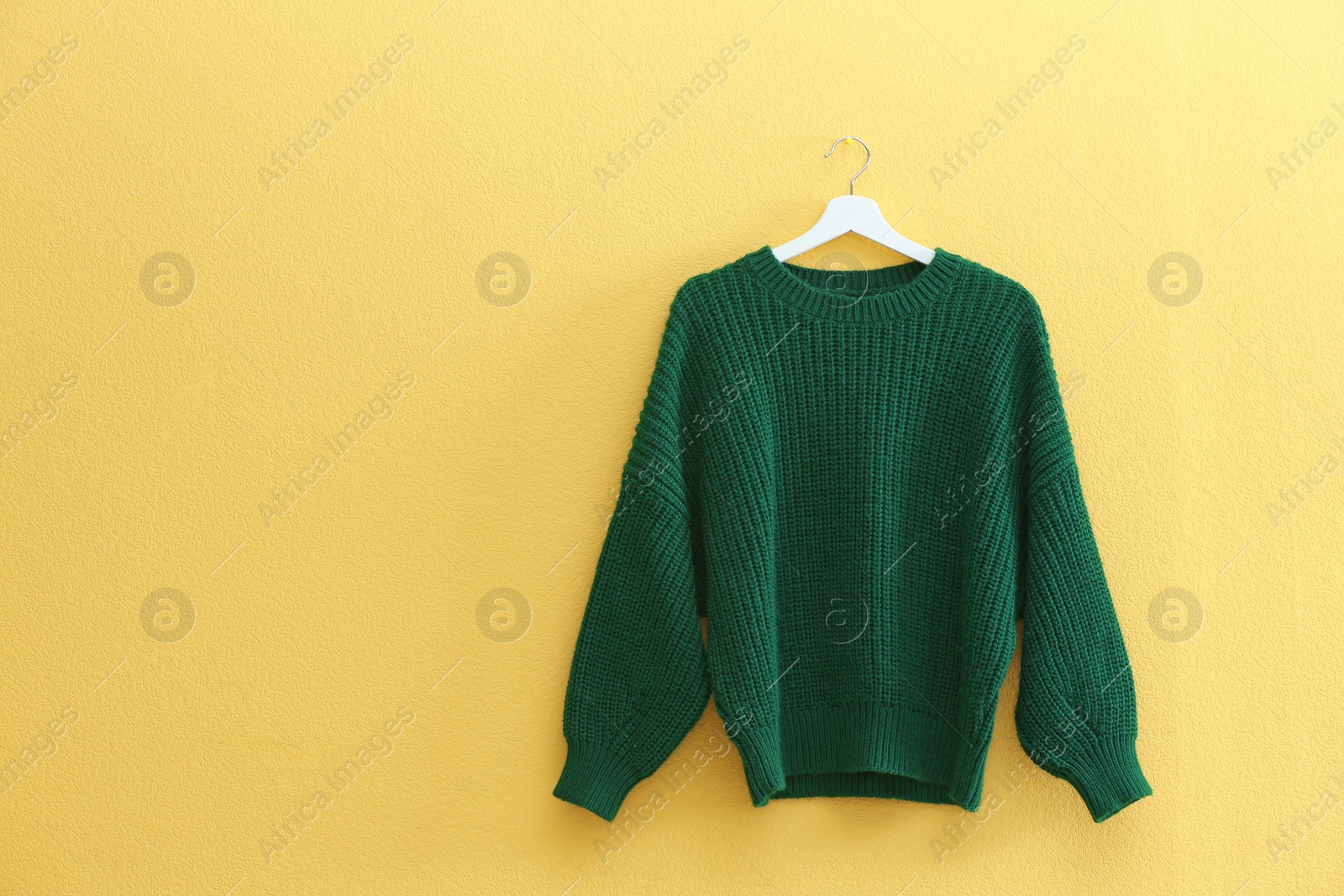 Photo of Hanger with stylish sweater on yellow wall