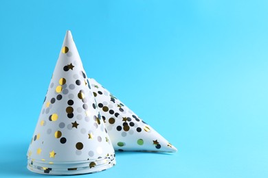 Photo of Party hats on light blue background, space for text